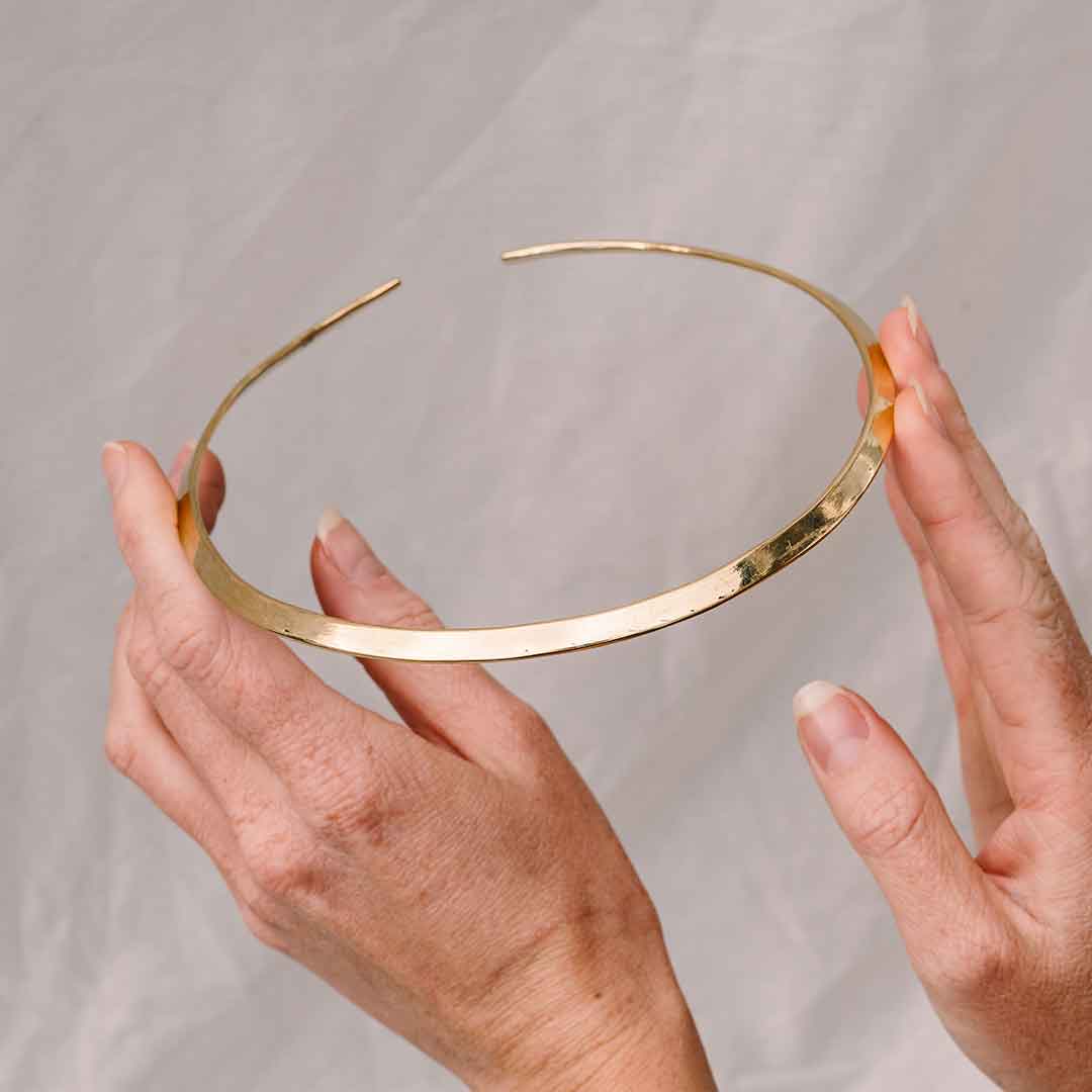 Auf diesesm Bild wird der goldene Halsreif von zwei Händen gehalten.