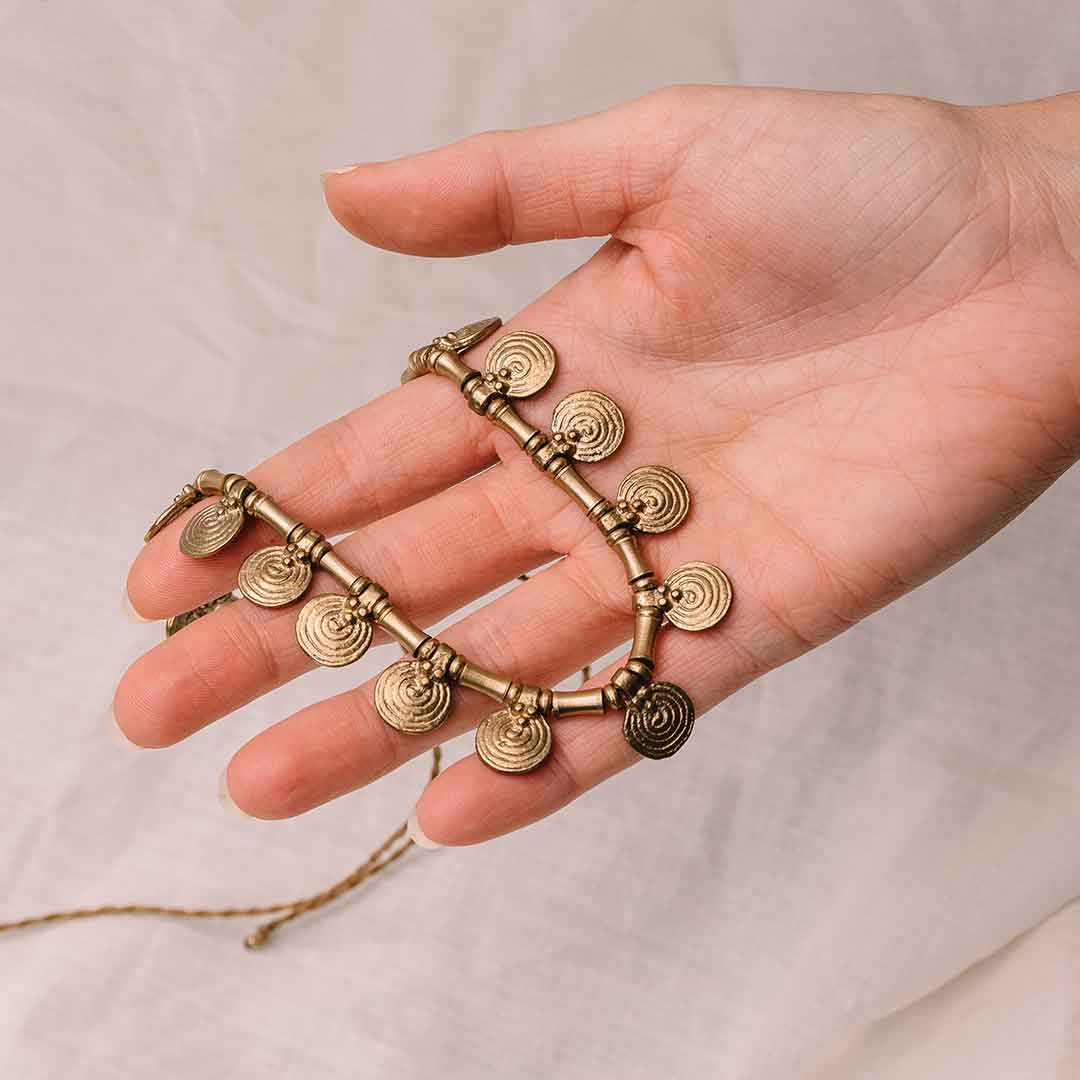 In diesem Bild sieht man wie eine Hand die Boho Messing Halskette hält.