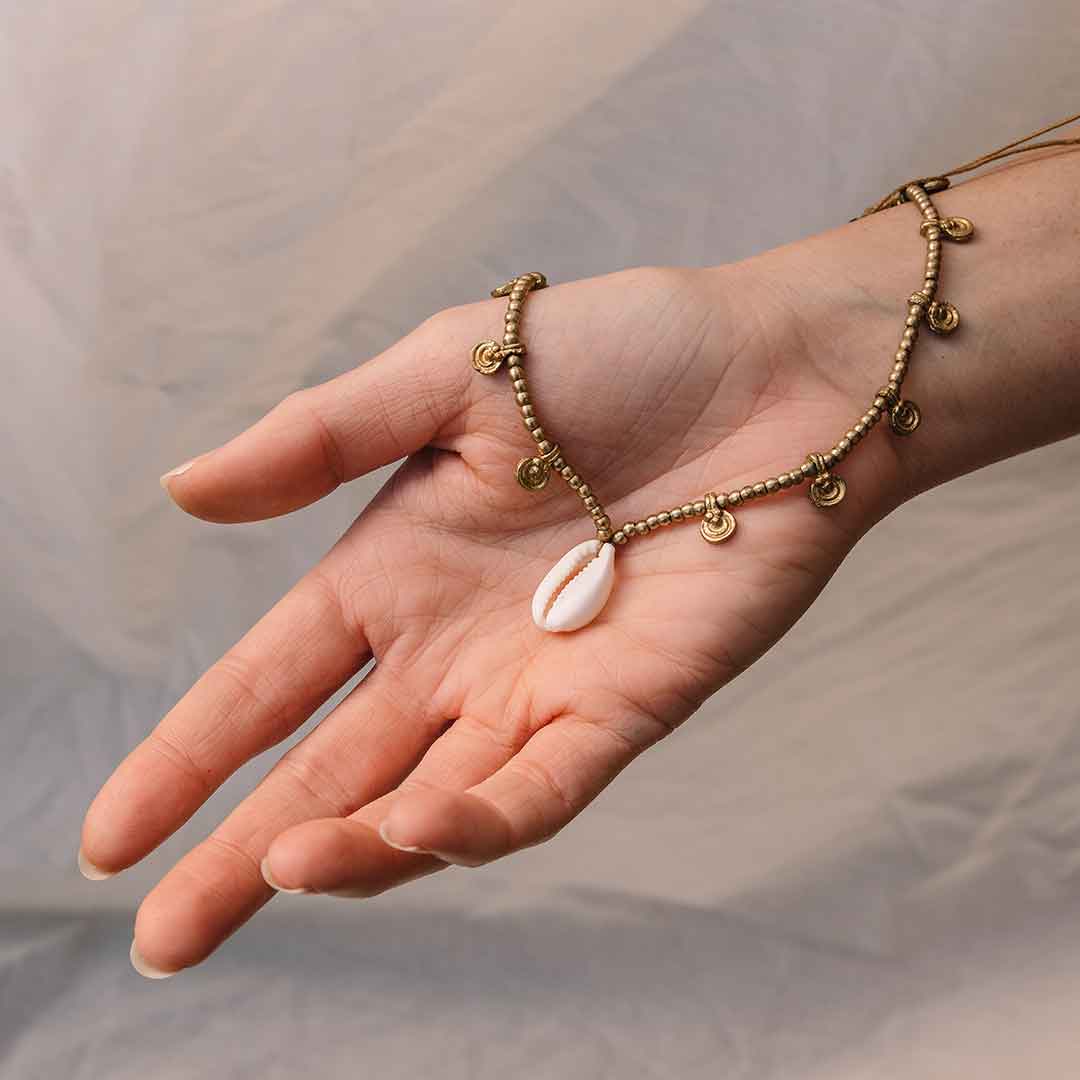 Auf diesem Bild zeigt eine Hand den Muschel Anhänger der Kette.
