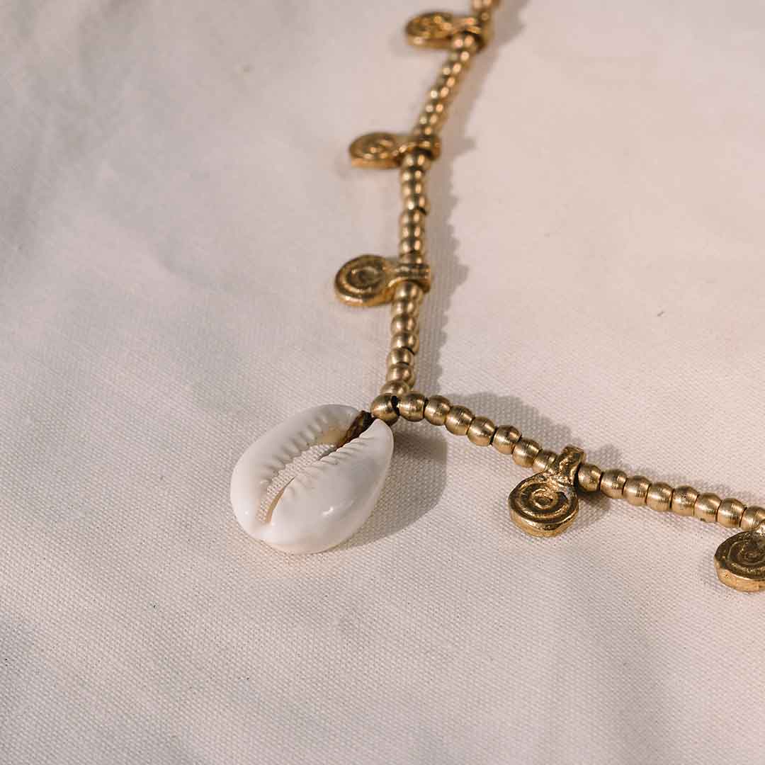 Dieses Bild zeigt die Muschel Kette im Detail mit goldenen Messing Anhängern und Kauri Muschel.