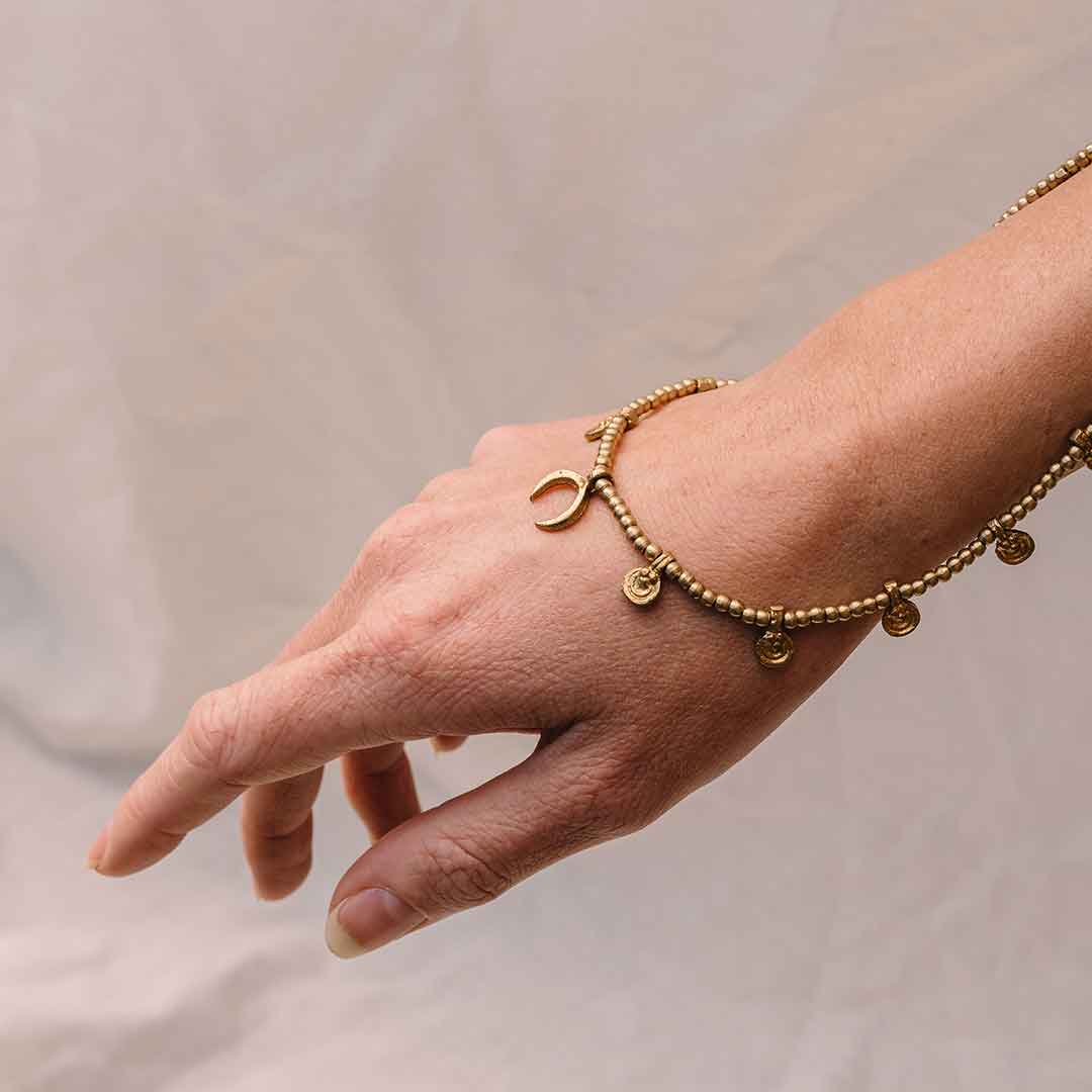 Dieses Bild zeigt wie eine Hand die Mond Halskette in Gold von einem weißen Hintergrund hält.