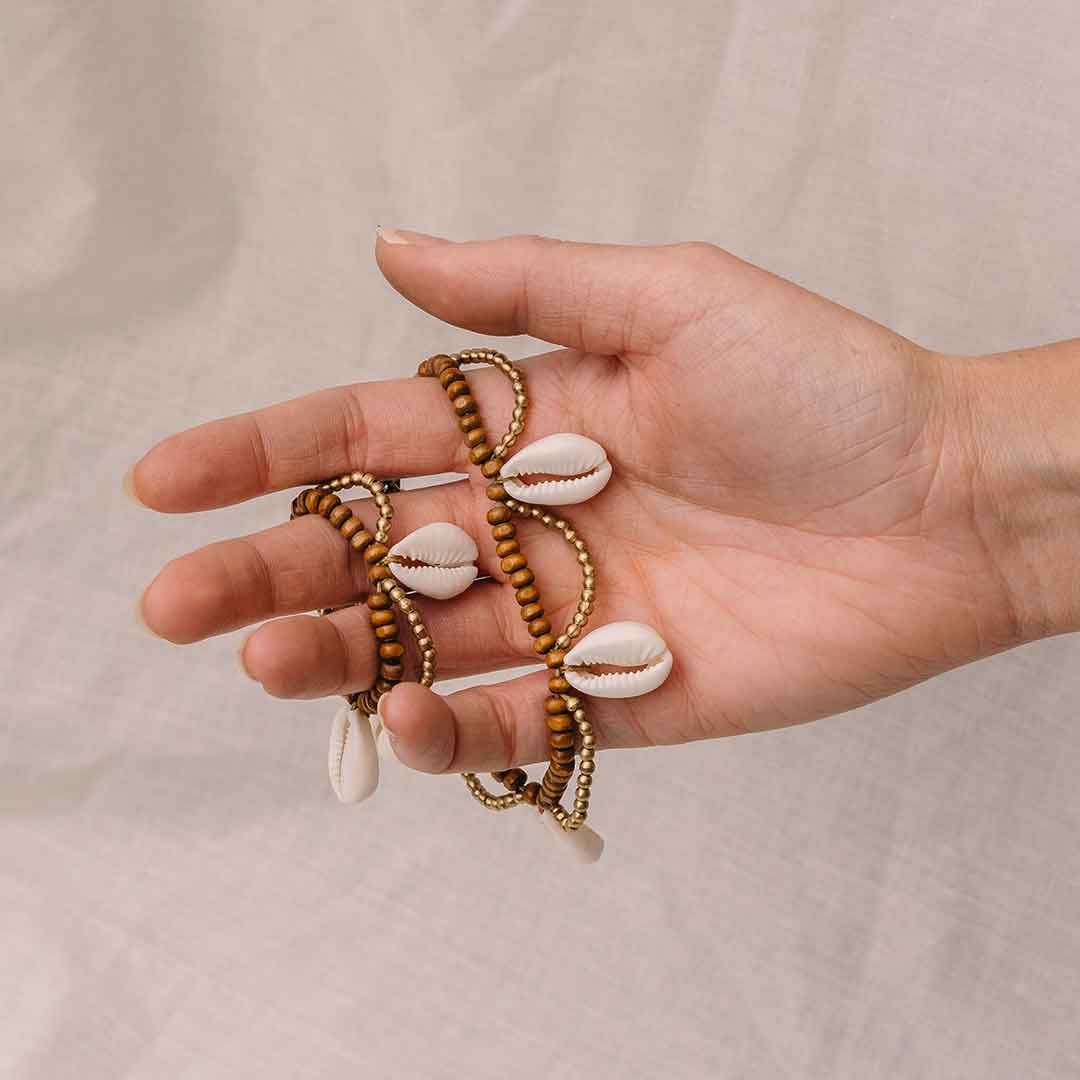 Auf diesem Bild hält eine Hand die Muschel Perlenkette fest.