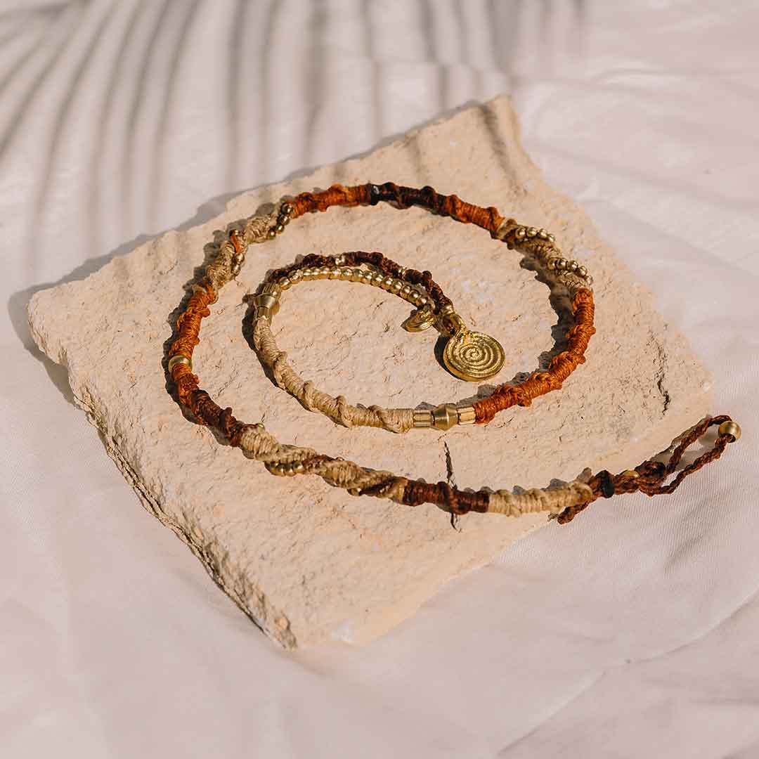 Auf diesem Bild sieht man die Hairwrap mit Messinganhängern auf einem Sandstein liegen.