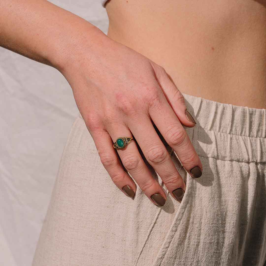 Das Bild zeigt den Ring mit grünem Stein am Finger einer Frau getragen.