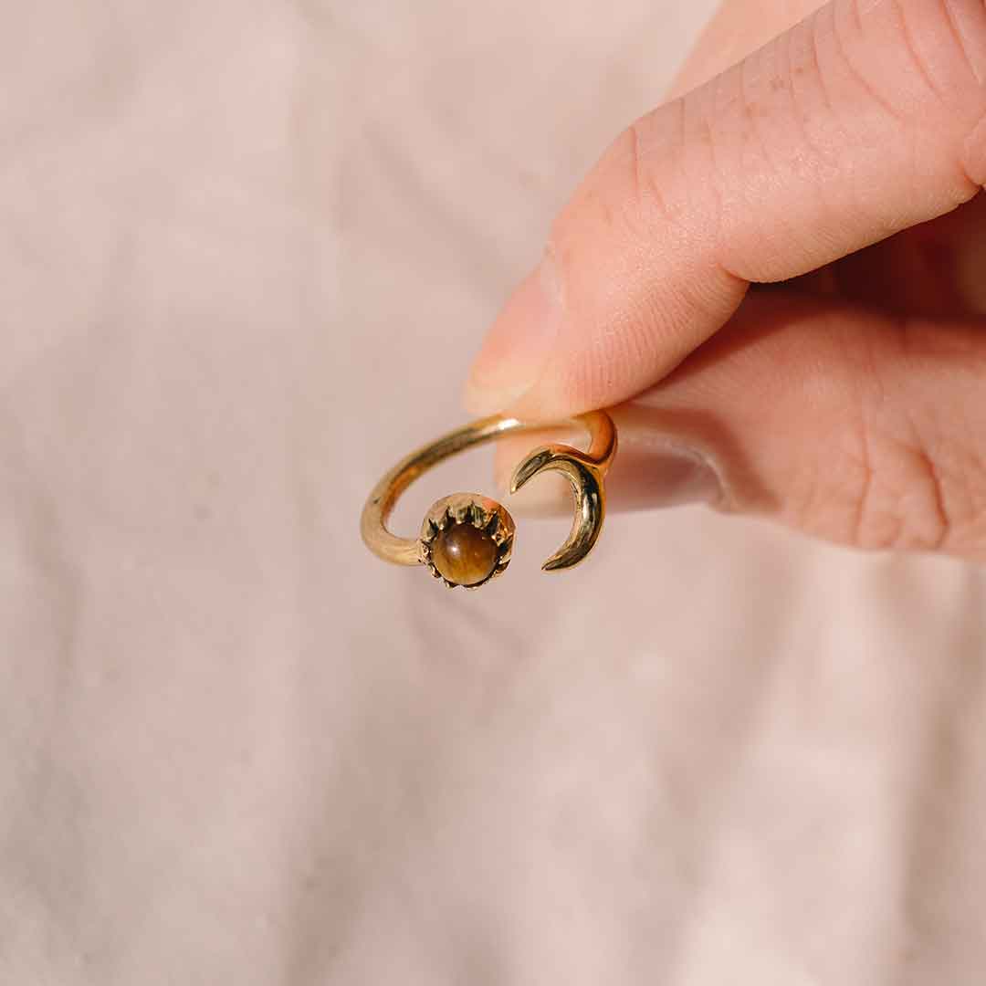 In diesem wird der goldene Mond Ring mit Tigerauge von einer Hand gehalten.