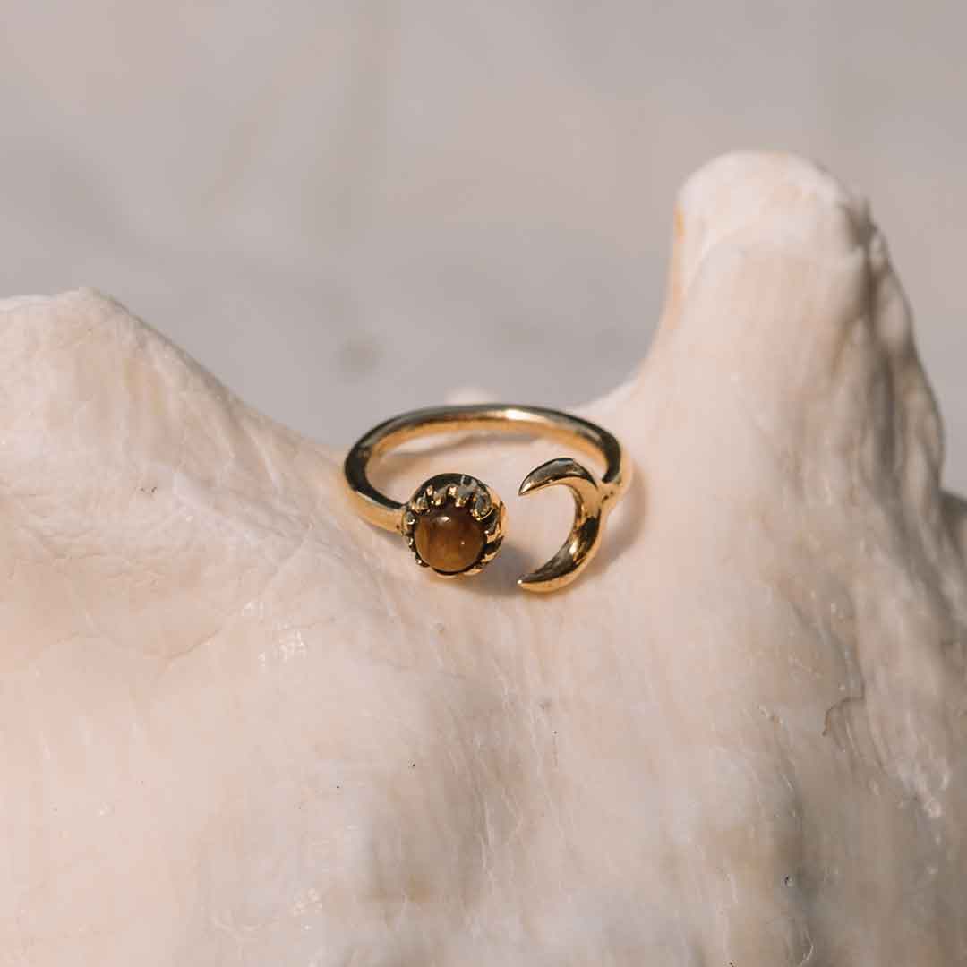 In diesem Bild wird der Tigerauge Mond Ring auf einem Stein dargestellt.
