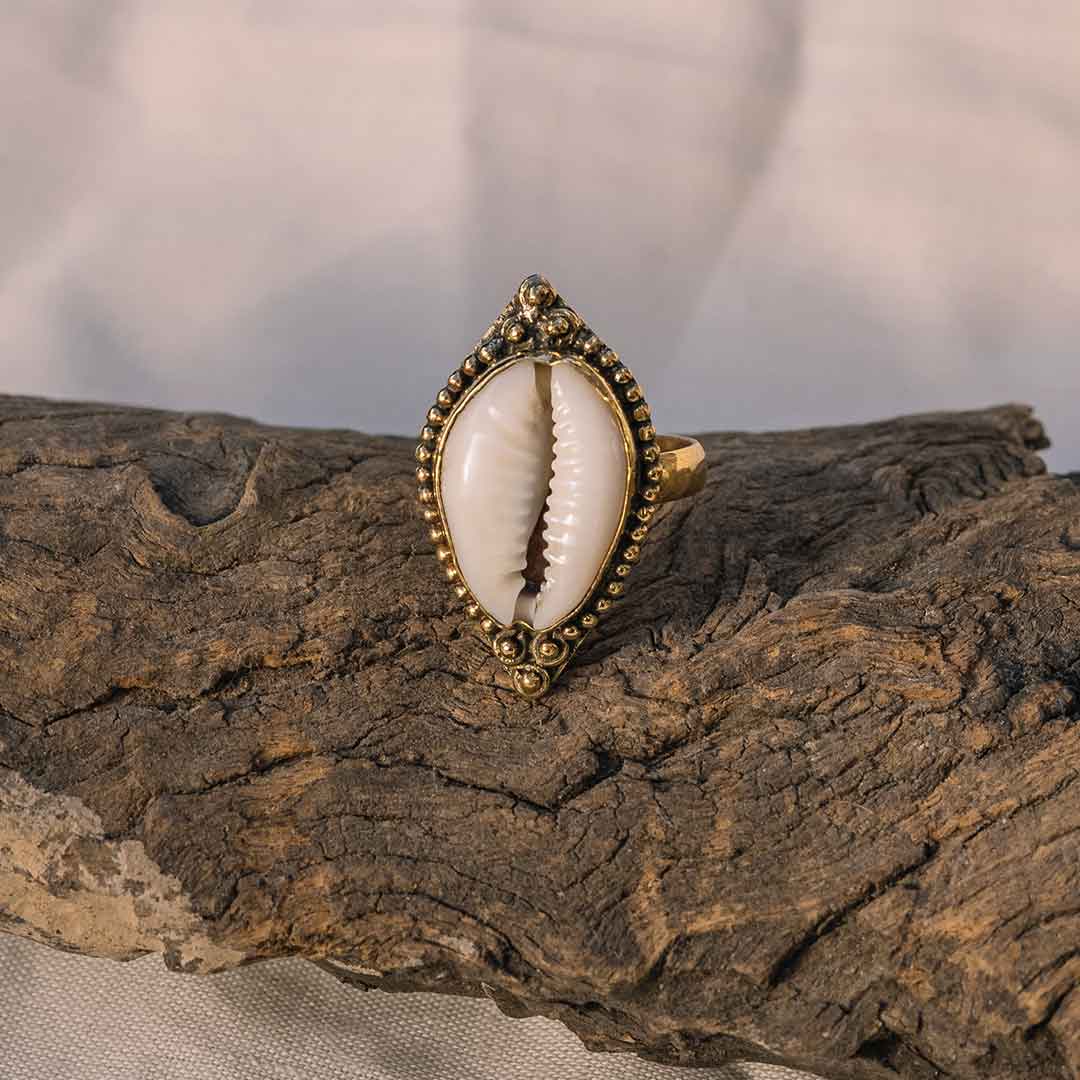 Auf diesem Bild sieht man den goldenen Muschel Ring auf einem Holzstück.