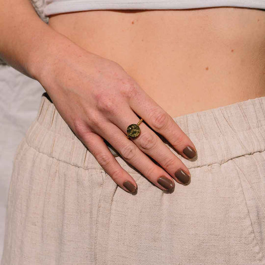 Auf diesem Bild sieht man den gehämmerten Ring in Gold an einem Finger einer Frau.